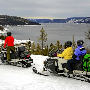 Snowmobilers with the Saguenay Fjord in the background